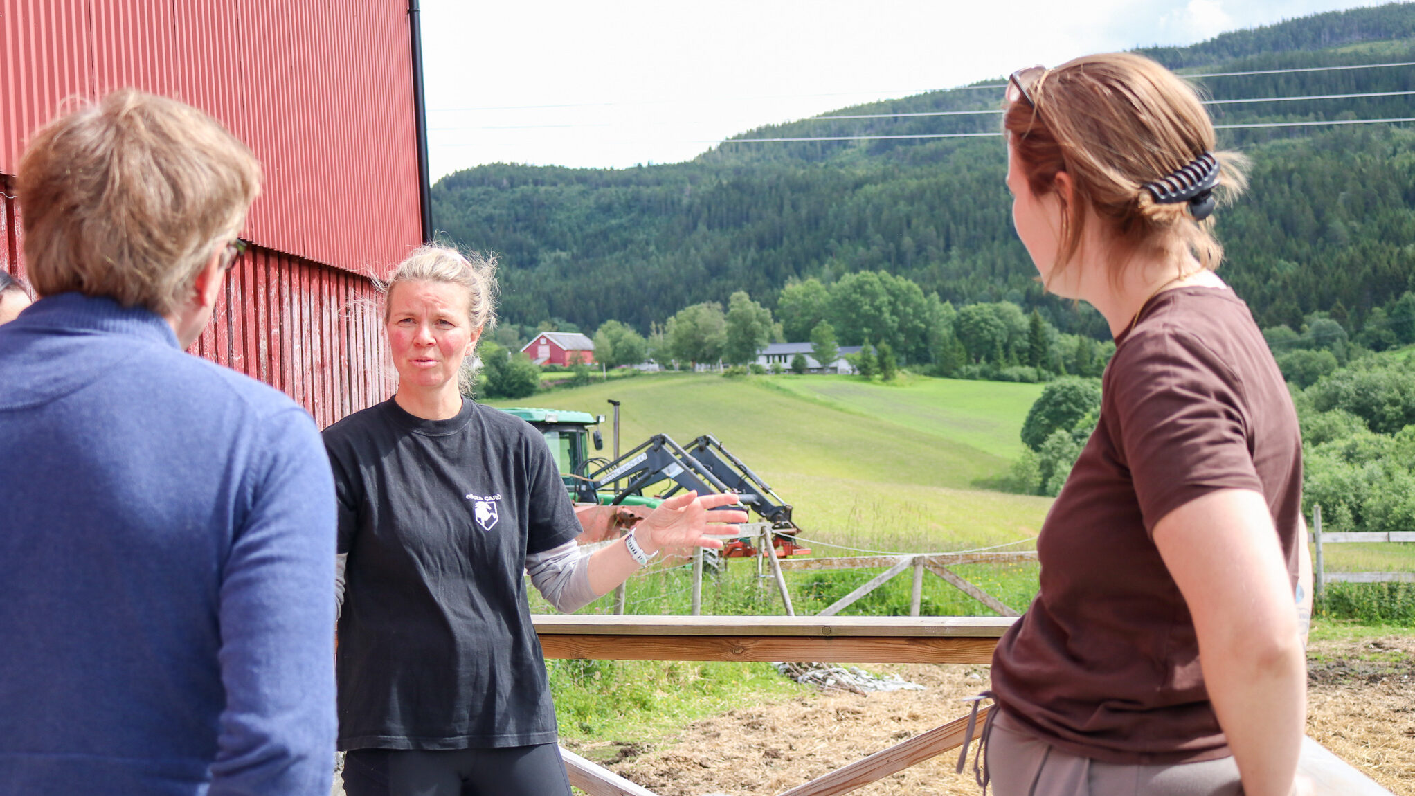 Bilde fra Eikra gård. På bildet står tre personer og snakker sammen. 