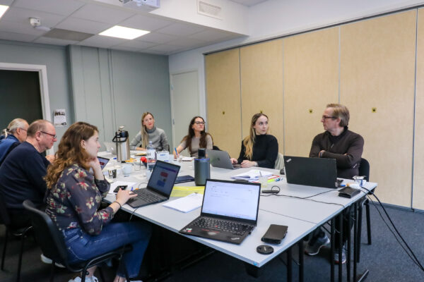 Bilde av en gruppe menneske som sitter rundt et bord og arbeider